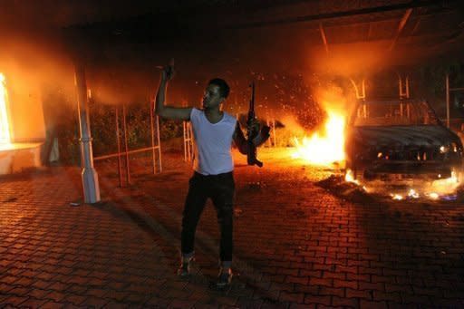 An armed man waves his rifle as buildings and cars are engulfed in flames after being set on fire inside the US consulate compound in Benghazi on September 11. Mitt Romney on Wednesday hit out at the Obama administration's "disgraceful" response to violent protests in Egypt and Libya, accusing it of sympathizing with the Islamist demonstrators