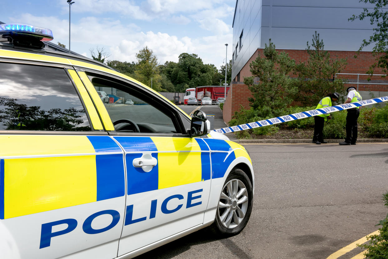 Police offices one female and one male and Police car at the scene of a possible crime with cordon tape around at the side of road