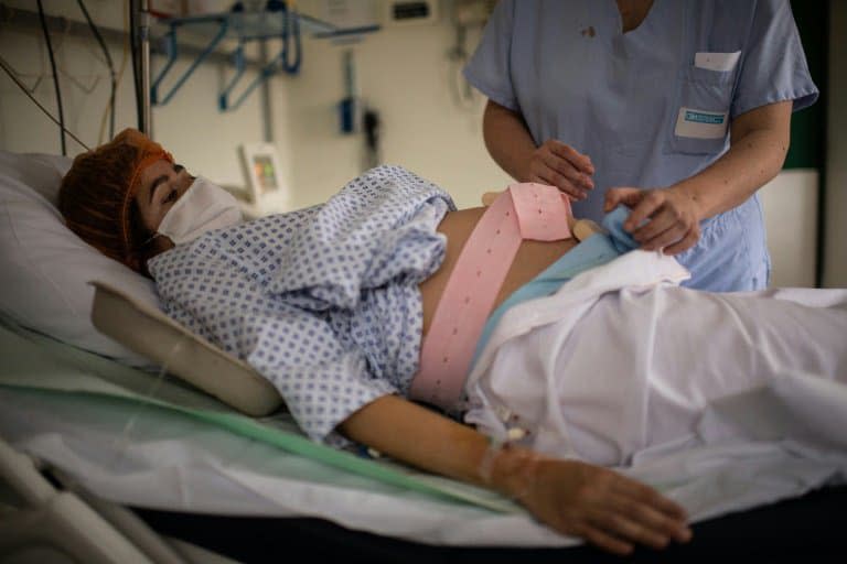 Une infirmière s'occupe d'une femme enceinte à la maternité des Diaconesses à Paris, le 17 novembre 2020 - Martin BUREAU © 2019 AFP