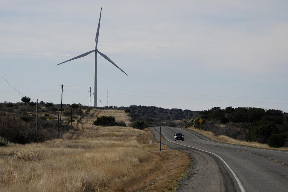 A vehicle a wind turbine, Friday, Feb. 17, 2023, near Del Rio, Texas. Some landowners along the Devil's River argue that proposed wind turbines would kill birds, bats and disrupt monarch butterflies migrating to Mexico and impact ecotourism, a main source of income for many. (AP Photo/Eric Gay)