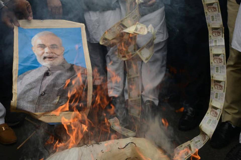 Supporters of the opposition Congress burn old 500 rupee notes and a poster bearing the image of prime minister Narendra Modi during a protest against demonetisation (AFP via Getty Images)