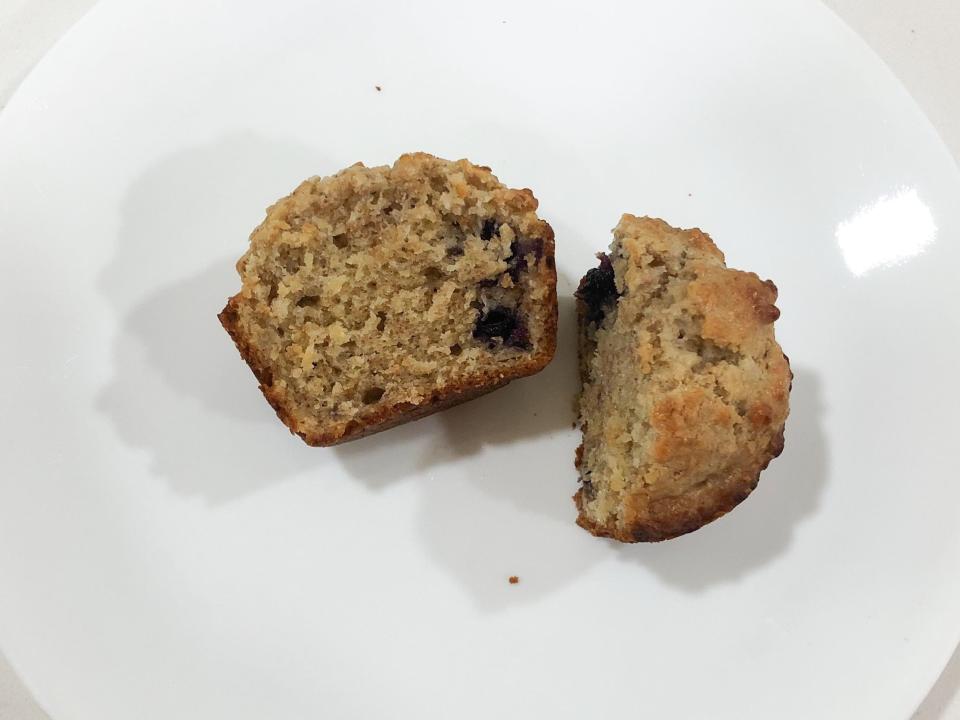 A blueberry-bran muffin sliced in half on a white plate.