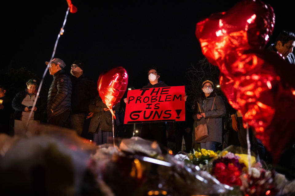 At the community candlelight vigil at Monterey Park City Hall, a man holds a sign reading: The Problem Is Guns!