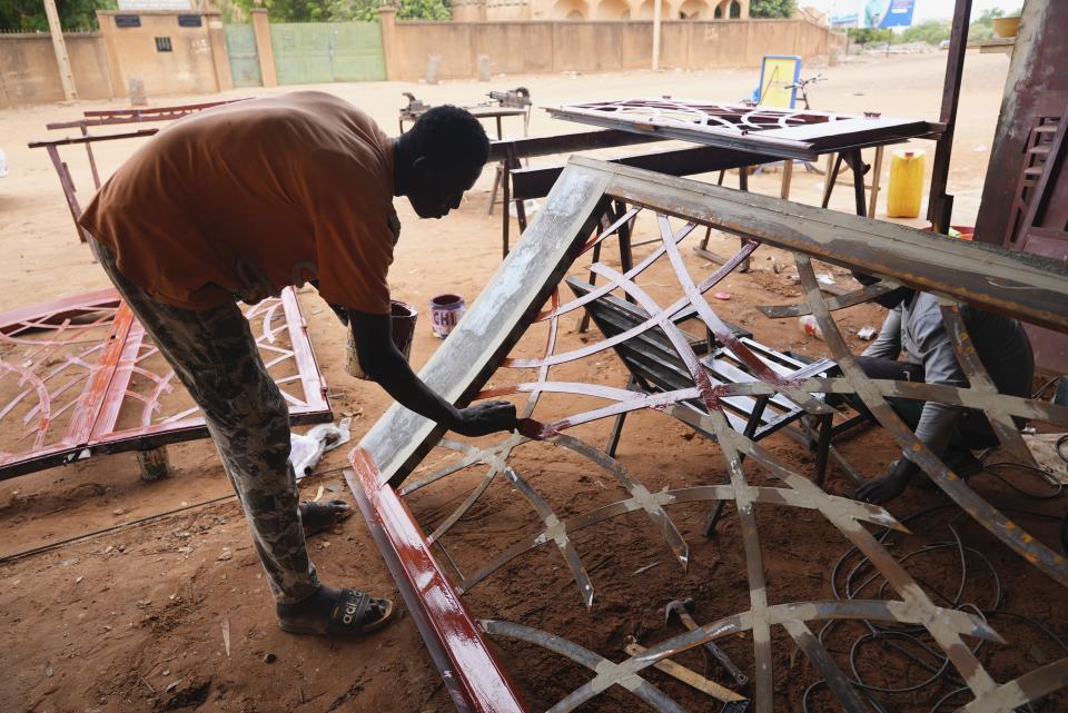 A man paints a gate in Niamey, Niger, Tuesday, Aug. 15, 2023. Niger, an impoverished country of some 25 million people, was seen as one of the last countries that Western nations could partner with in Africa's Sahel region to beat back a jihadi insurgency linked to al-Qaida and the Islamic State group. Before last month's coup, Europe and the United States had poured hundreds of millions of dollars into propping up its military. (AP Photo/Sam Mednick)