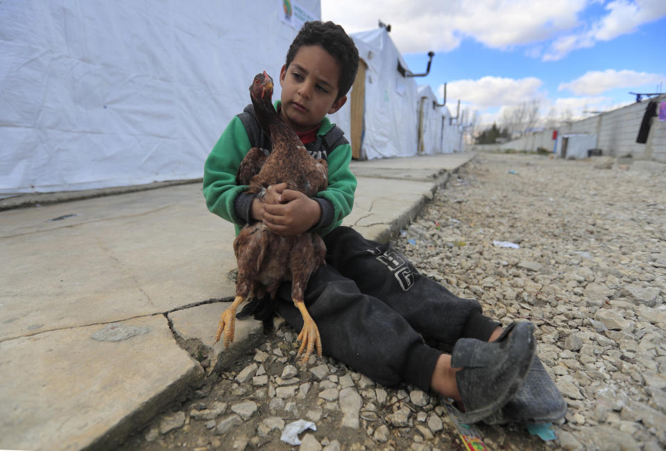 A displaced Syrian boy holds a chicken, as he sits outside his family's tent, at a refugee camp in Bar Elias, Bekaa Valley, Lebanon, Friday, March 5, 2021. UNICEF said Wednesday, March 10, 2021 that Syria’s 10-year-long civil war has killed or wounded about 12,000 children and left millions out of school in what could have repercussions for years to come in the country. The country's bitter conflict has killed nearly half a million people, wounded more than a million and displaced half the country’s population, including more than 5 million as refugees. (AP Photo/Hussein Malla)