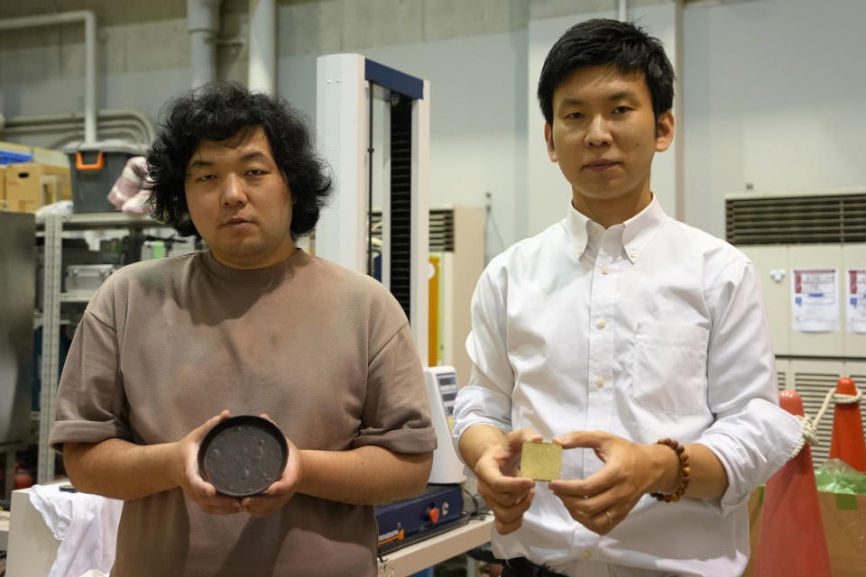 Tokyo University researchers Yuya Sakai, right, and Kota Machida pose for photos with products they made out of 'food cement' at their laboratory in Tokyo on May 26, 2022. Sakai and Machida developed a technology that can transform food waste into "cement" for construction use. (AP Photo/Chisato Tanaka)