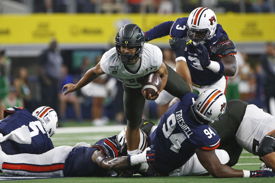 Oregon running back Travis Dye (26) runs for a short gain as Auburn defensive end Marlon Davidson (3) closes in during the first half of an NCAA college football game, Saturday, Aug. 31, 2019, in Arlington, Texas. (AP Photo/Ron Jenkins)