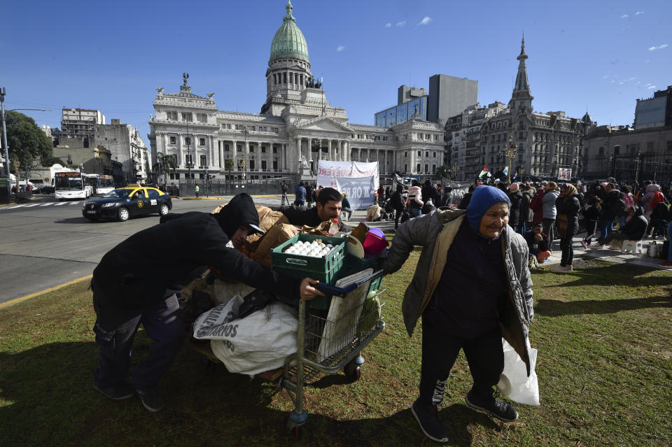 Vendedores ambulantes de comida llegan para instalar sus puestos frente al Congreso, donde se espera que los manifestantes se reúnan mientras los legisladores debaten las reformas respaldadas por el presidente Javier Milei en Buenos Aires, Argentina, el jueves 27 de junio de 2024. (AP Foto/Gustavo Garello)