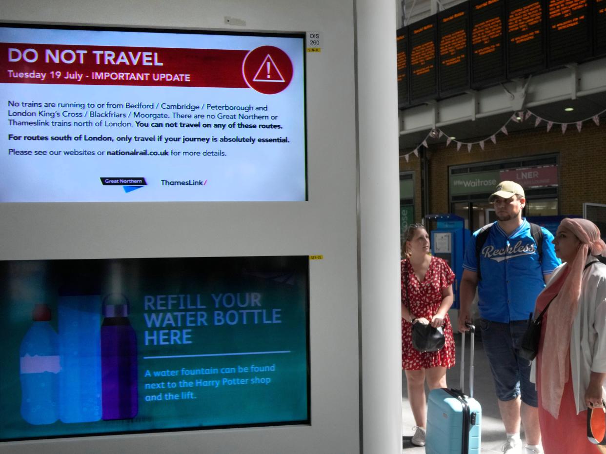 Passengers read information at King's Cross railway station where trains are canceled due to the heat in London, Tuesday, July 19, 2022.