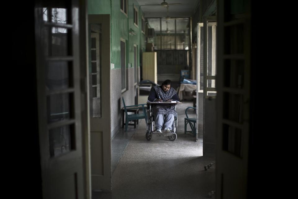 In this Sunday, Feb. 16, 2014, photo, Shamshad Kala, a Pakistani patient and resident at St. Joseph’s Hospice, studies English Grammar in a corridor near the female ward, in Rawalpindi, Pakistan. Mohammed Aqeel spent weeks at home in Pakistan waiting for death after suffering a debilitating spinal cord injury in a car crash before friends suggested he come to St. Joseph’s Hospice on the outskirts of the capital, Islamabad. Now 13 years later, his life and those of some 40 others who live on its grounds might be changed forever as this hospital of last resort faces closure over its rising debts. (AP Photo/Muhammed Muheisen)