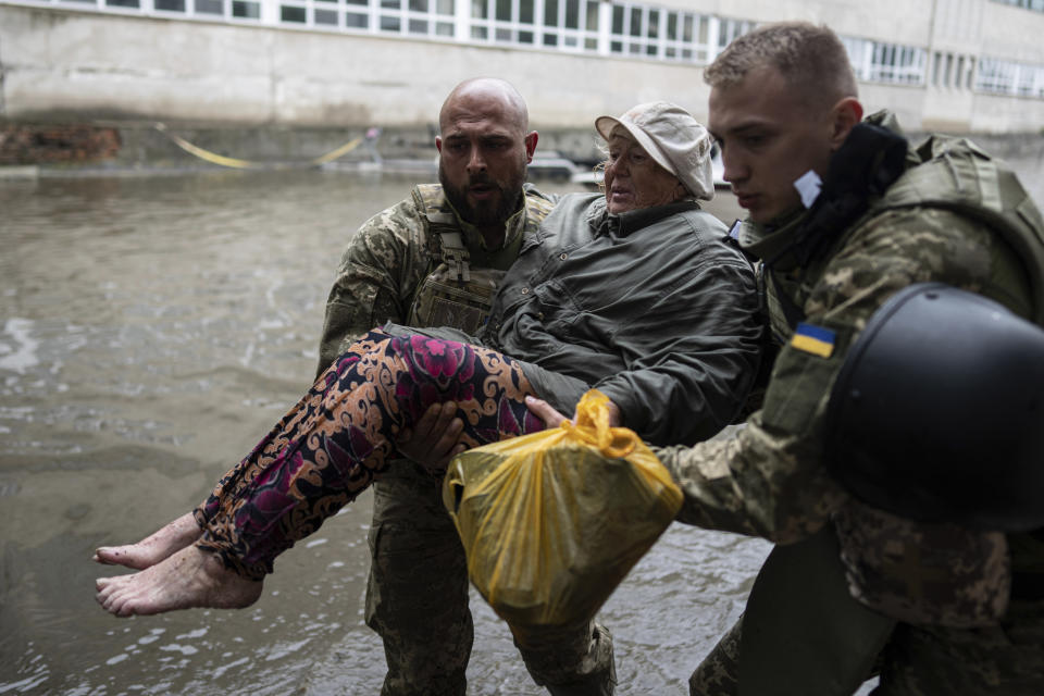Ukrainian servicemen help rush to safety an injured civilian evacuee who had came under fire from Russian forces while trying to flee by boat from the Russian-occupied east bank of a flooded Dnieper River to Ukrainian-held Kherson, on the western bank in Kherson, Ukraine on Sunday, June 11, 2023. (AP Photo)