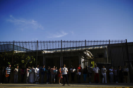 People listen to a U.S. Embassy employee (back to camera) prior to entering the complex, where they will have their documentation revised prior to their appointment at a U.S. Embassy in a third country, in Havana, Cuba, August 22, 2018. REUTERS/Alexandre