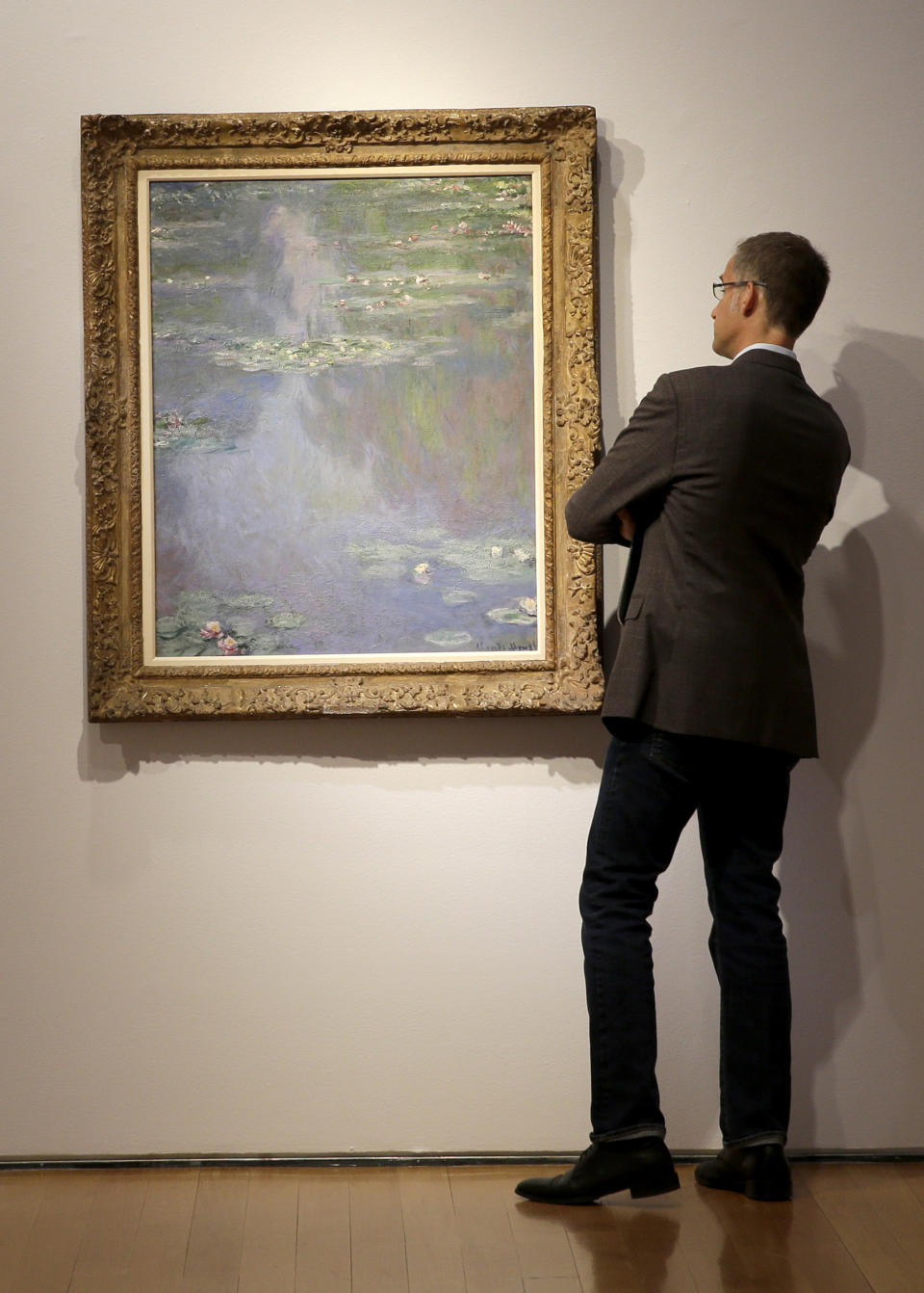 A man gets a closer look at "Nympheas" by Claude Monet during an auction preview at Christie's in New York, Tuesday, May 6, 2014. Works from the estates of heiress Huguette Clark, Edgar Bronfman and other major collectors are leading New York City’s spring art auctions. The sale of impressionist and modern art begins Tuesday evening at Christie’s. The auction house says it expects to raise over $245 million. (AP Photo/Seth Wenig)