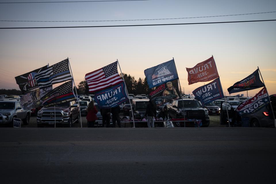 People selling Trump souvenirs fly flags at a parking lot near the venue of his rally, Monday, Nov. 2, 2020, in Kenosha, Wis. Trump has made Wisconsin a focus of his final push, including a stop planned Monday night in Kenosha, while repeatedly refusing to say whether he would agree to a peaceful transfer of power if he loses. (AP Photo/Wong Maye-E)