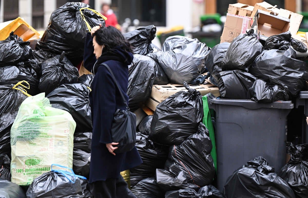 A pedestrian walks past mounds of uncollected rubbish in Paris (AFP via Getty Images)