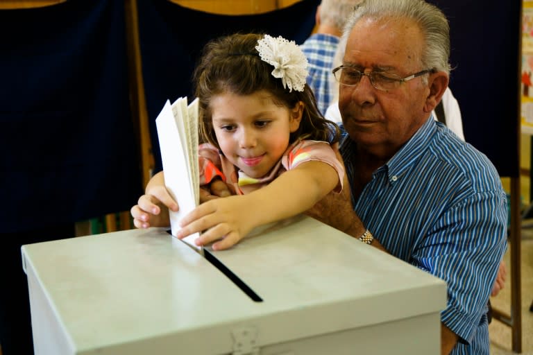 A Cypriot girl casts the ballot of her relative for the parliamentary elections at a polling station in the capital Nicosia on May 22, 2016