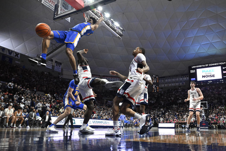 Xavier's Desmond Claude dunks over UConn's Adama Sanogo, left, and Jordan Hawkins, right, in the first half of an NCAA college basketball game, Wednesday, Jan. 25, 2023, in Storrs, Conn. (AP Photo/Jessica Hill)