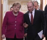 Russian President Vladimir Putin and German Chancellor Angela Merkel arrive for a joint news conference in the Kremlin in Moscow