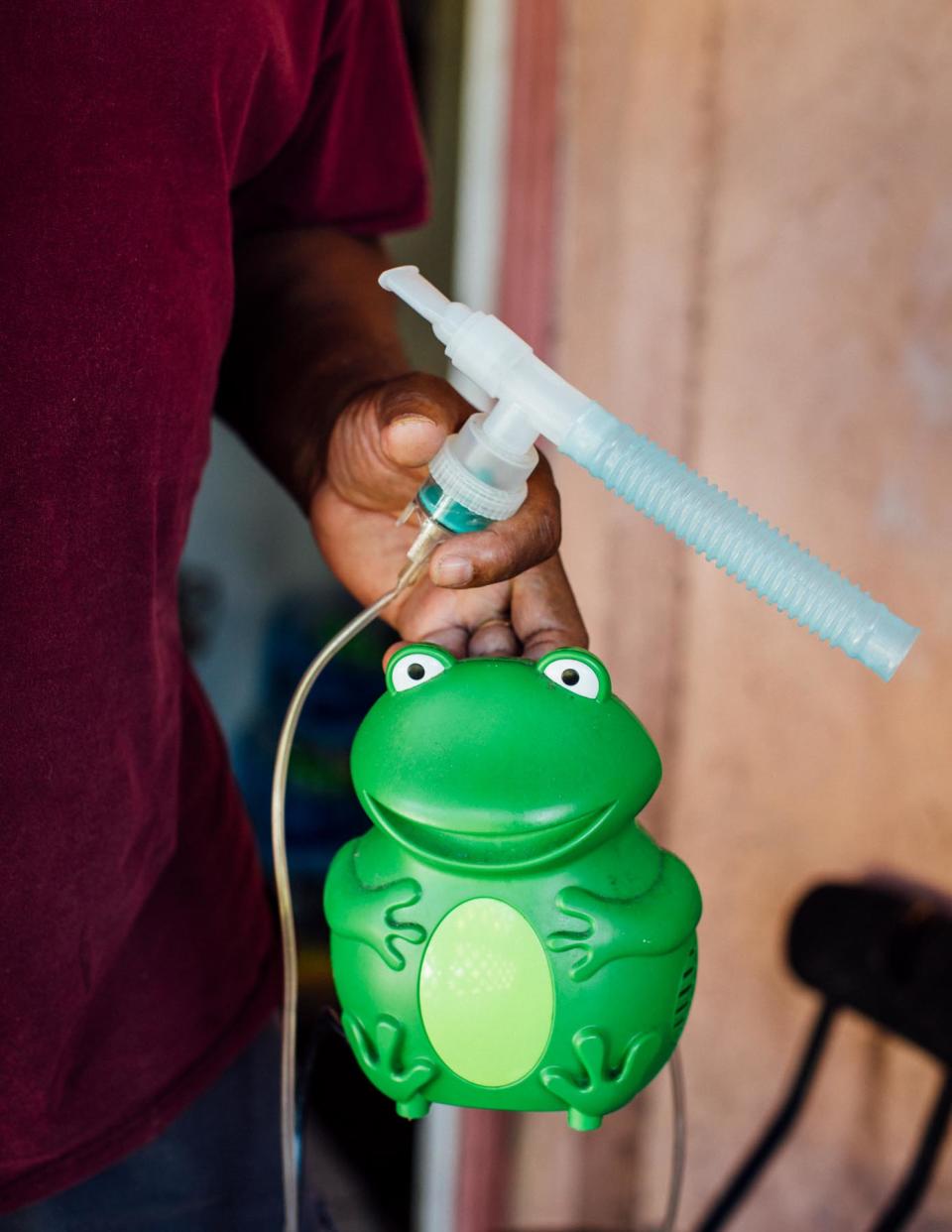 Ed Jones holds the nebulizer used by his teenage granddaughter. His whole family deals with respiratory issues while living close to burning cane in Pahokee, Florida.