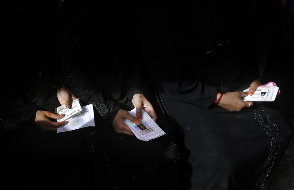 FILE - In this Thursday, April 11, 2019 file photo, Indian Muslim women hold their identification cards as they wait to cast their votes during the first phase of general elections near Ghaziabad, in Uttar Pradesh state, India. The final phase of India’s marathon general election will be held on Sunday, May 19. The first of the election’s seven staggered phases was held on April 11. Vote counting is scheduled to start on May 23. India has 900 million eligible voters. (AP Photo/Manish Swarup, File)