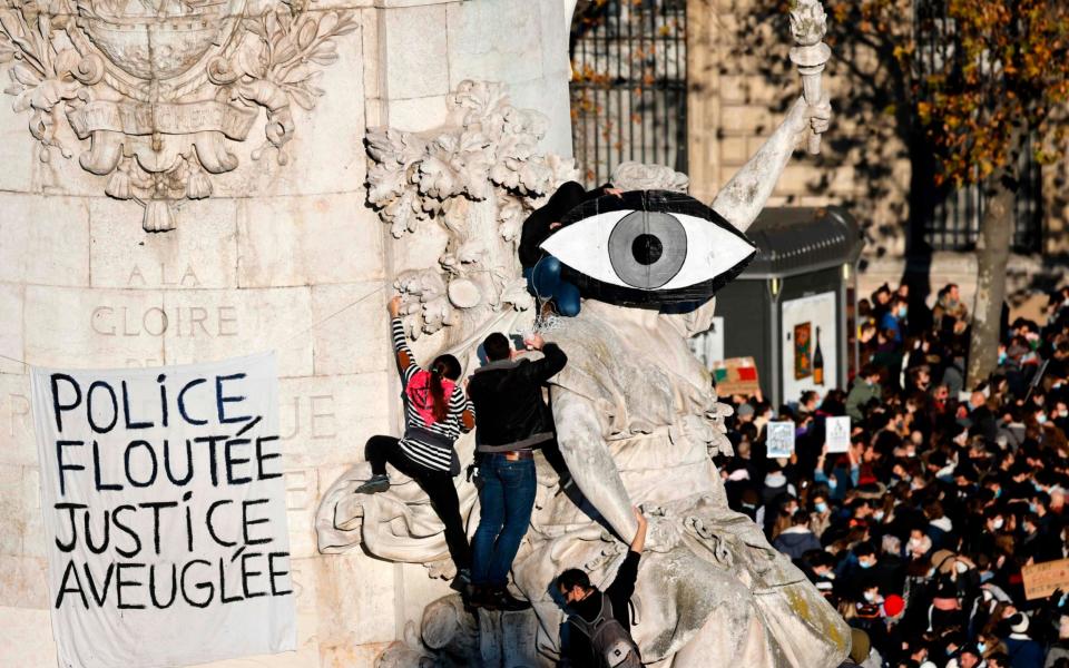 Demonstrators climb on the statue 'Le Triomphe de la Republique' - THOMAS COEX/AFP via Getty Images