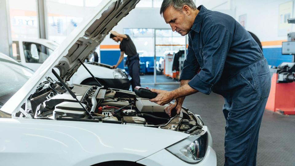 Car mechanic with diagnostic device for reading the error codes.