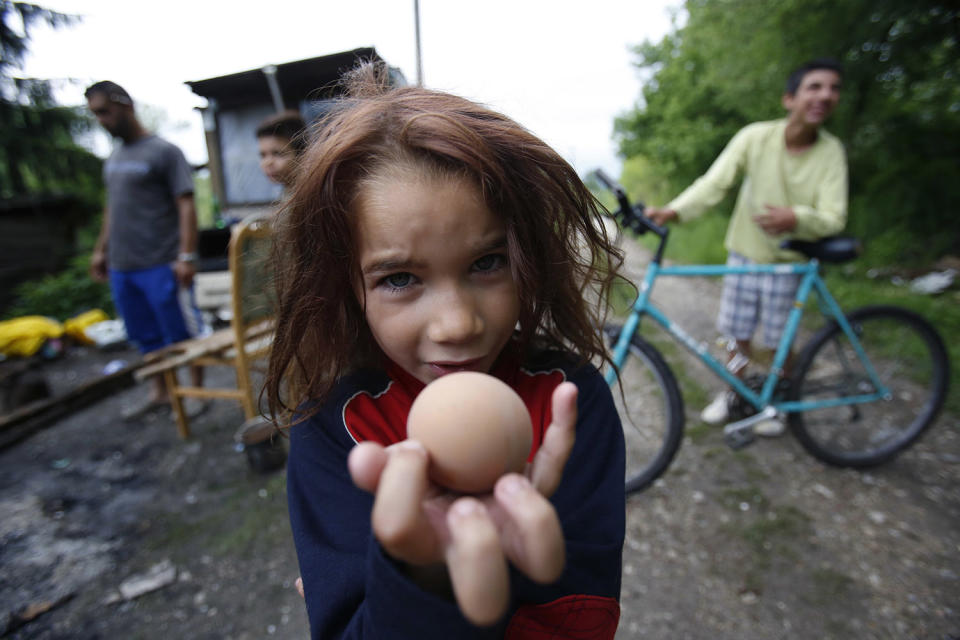 <p>Roma girl Samira Ramic poses for photo as she shows a boiled egg, during St. George’s Day celebration with her family members, in the village of Kiseljak, near Tuzla,140 kms north of Sarajevo, May 6, 2017. Members of the Roma minority community in Bosnia and Herzegovina celebrated their biggest holiday, St. George’s Day, or Djurdjevdan, with traditional rituals such as taking baths and washing hands with water from church wells and cracking eggs, as the holiday marks the advent of spring. (Photo: Amel Emric/AP) </p>