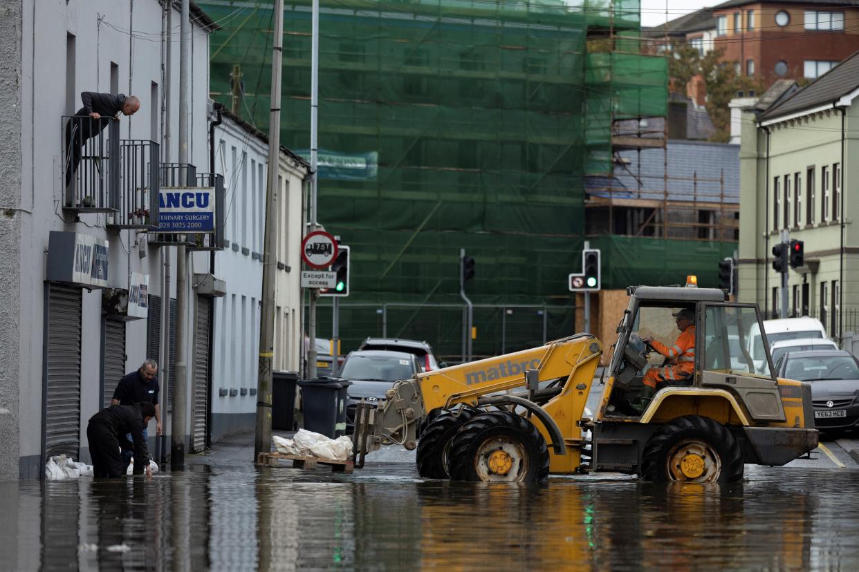 People receive assistance from a digger to sandbag their home as water flows through the streets of Newry (REUTERS)