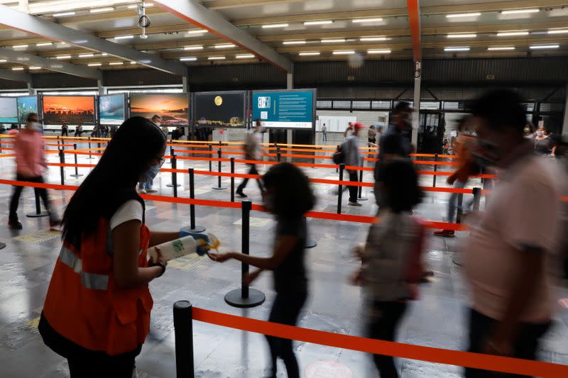 A metro employee dispenses disinfectant gel to commuters inside the metro, as the government plans to start easing restrictions amid the outbreak of the coronavirus disease (COVID-19) in Mexico City,