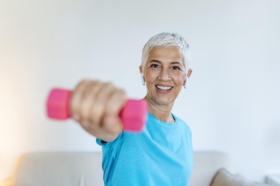 Physical activity can significantly impact your quality of life during menopause. (Getty) Senior woman exercise with dumbbells at home . happy mature woman doing arm workout using dumbbells. Elderly woman prefers healthy lifestyle