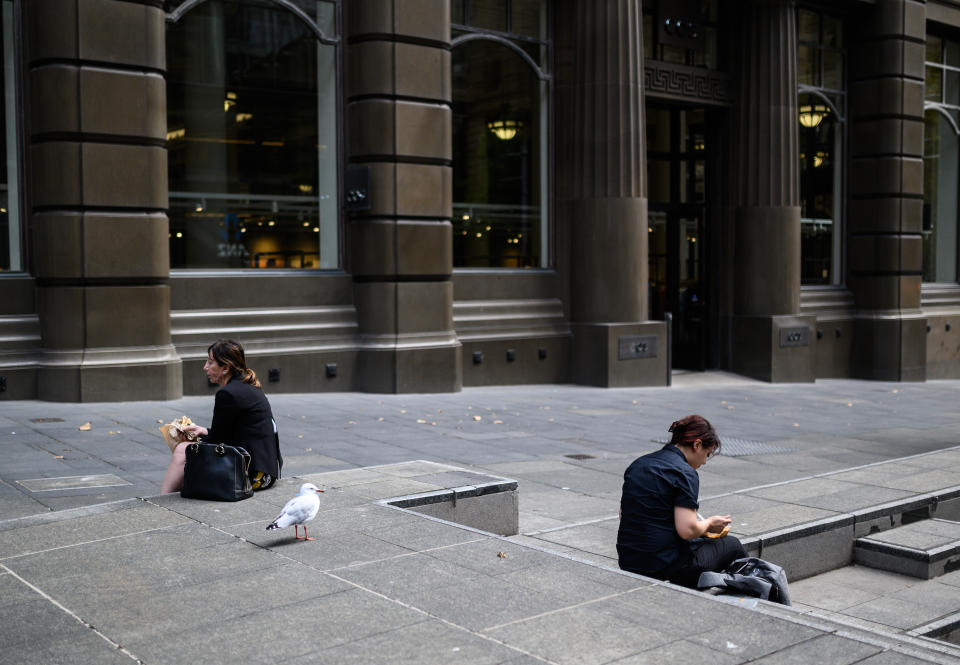 Two people sit a distance apart eating lunch in Martin Place, Sydney