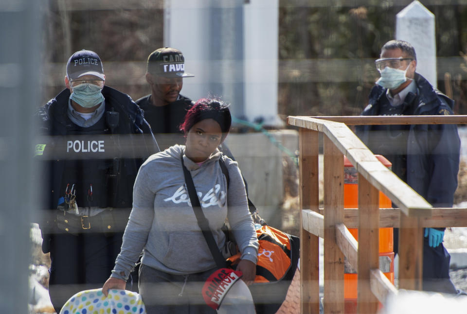 FILE - In this March 18, 2020, file photo, asylum seekers cross the border from New York into Canada at Roxham Road in Hemmingford, Quebec. The Trump administration on Wednesday, July 8, 2020, proposed empowering border authorities to deny asylum to people from countries with widespread, deadly communicable disease, its latest in a string of regulations before the November elections to dramatically raise the bar on who qualifies for humanitarian protections. (Ryan Remiorz/The Canadian Press via AP, File)