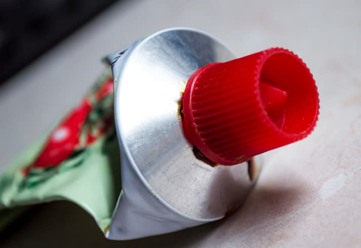 Close-up of a metal toothpaste tube with a red cap