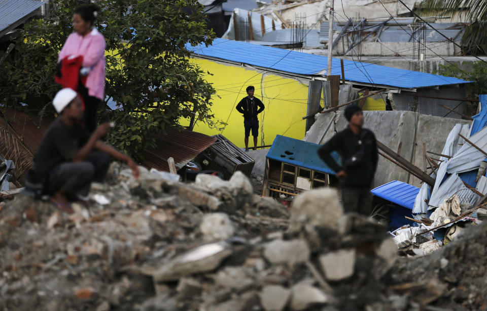 People watch as rescuers search for victims of Sept. 28 earthquake at Balaroa neighborhood in Palu, Central Sulawesi, Indonesia, Wednesday, Oct. 10, 2018. Indonesia's disaster agency said Wednesday that it only needs tents, water treatment units, generators and transport from other countries as it responds to the Sulawesi earthquake and tsunami that killed more than 2,000 people. (AP Photo/Dita Alangkara)