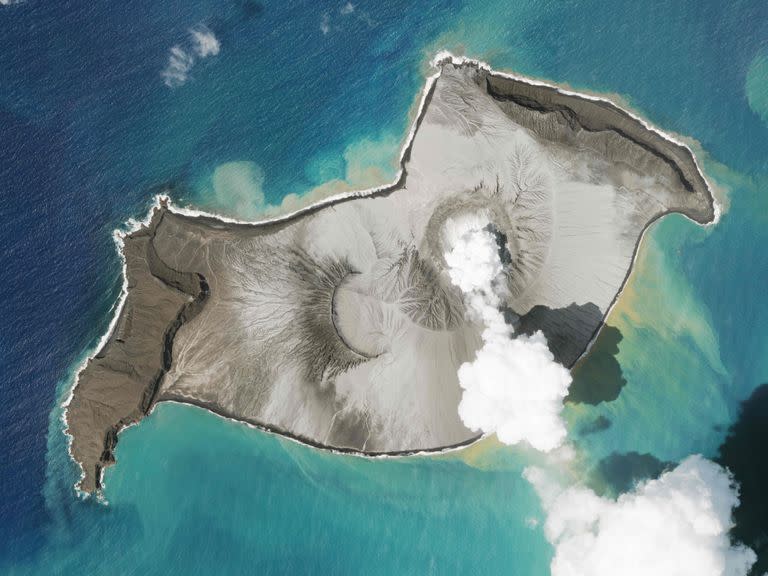 In this satellite photo taken by Planet Labs PBC, an island created by the underwater Hunga Tonga Hunga Ha&#39;apai volcano is seen smoking Jan. 7, 2022. An undersea volcano erupted in spectacular fashion near the Pacific nation of Tonga on Saturday, Jan. 15, sending large tsunami waves crashing across the shore and people rushing to higher ground. A tsunami advisory was in effect for Hawaii, Alaska and the U.S. Pacific coast, with reports of waves pushing boats up in the docks in Hawaii. (Planet Labs PBC via AP)