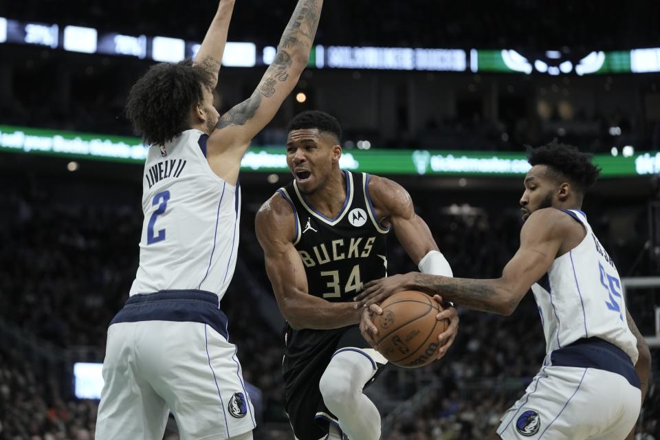 Milwaukee Bucks' Giannis Antetokounmpo is fouled driving between Dallas Mavericks' Derrick Jones Jr. and Dereck Lively II during the second half of an NBA basketball game Saturday, Nov. 18, 2023, in Milwaukee. The Bucks won 132-125. (AP Photo/Morry Gash)