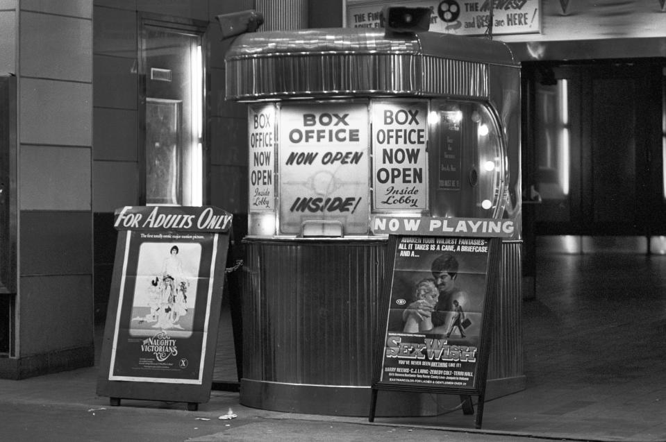 Vintage movie theater box office with promotional posters and "Box Office Open" signs