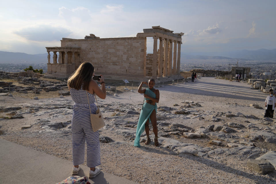 FILE - In this Tuesday, June 8, 2021 file photo, a tourist take photos at the Parthenon temple during a media tour for the Foreign Correspondents organised by the Greek Cultural Ministry at the Acropolis hill in Athens. Europe is opening up to Americans and other visitors after more than a year of COVID-induced restrictions. European governments hope to lure back tourists - and their dollars - back to the continent’s trattorias, vistas and cultural treasures. (AP Photo/Thanassis Stavrakis, File)