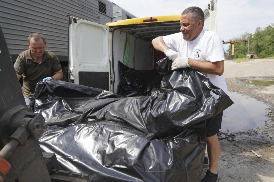 Ukraine's military official workers move bodies of killed Russian soldiers into a refrigerator in Kharkiv, Ukraine, Saturday, June 18, 2022. (AP Photo/Andrii Marienko)