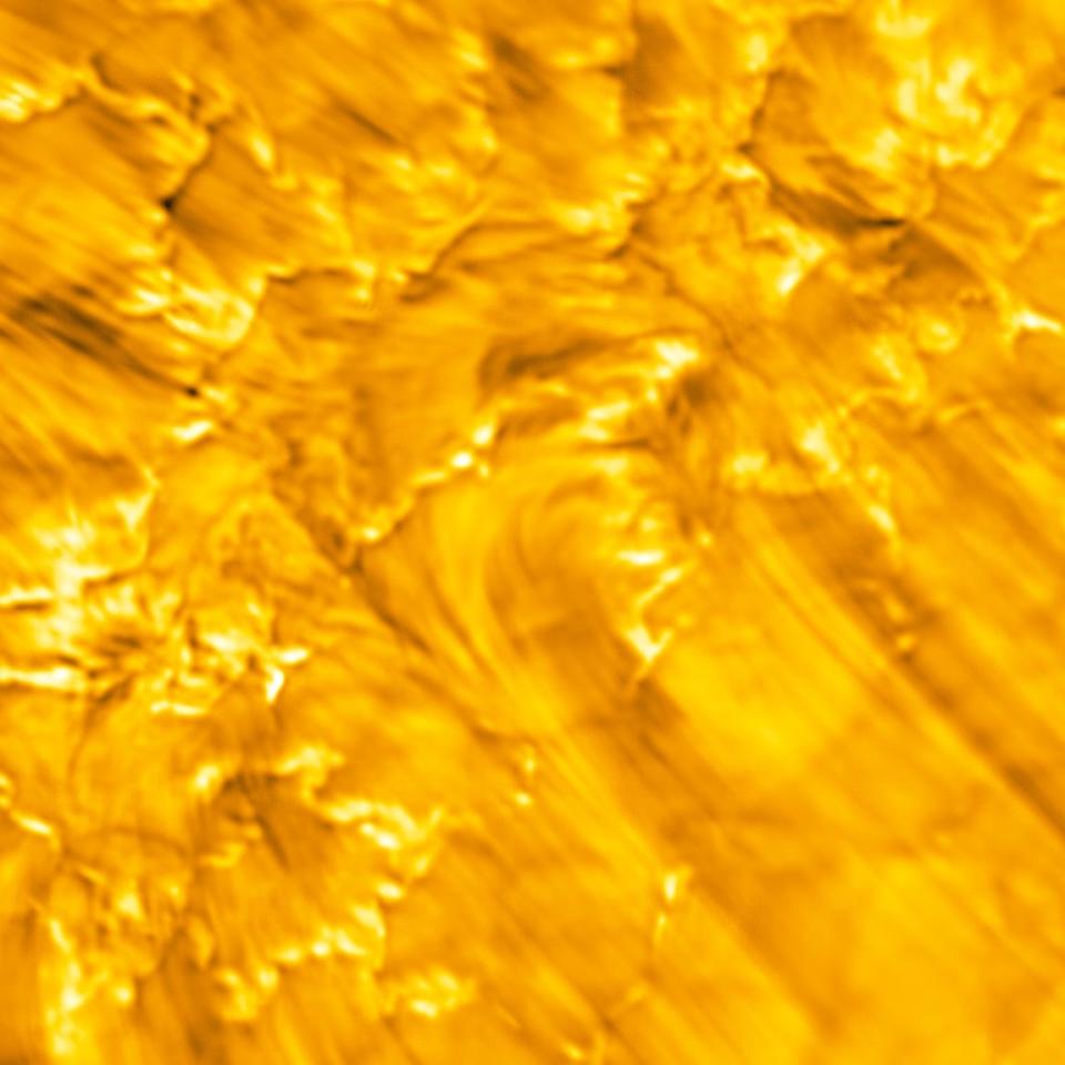 zoomed in section of the bright yellow solar surface with faint whispy stripes