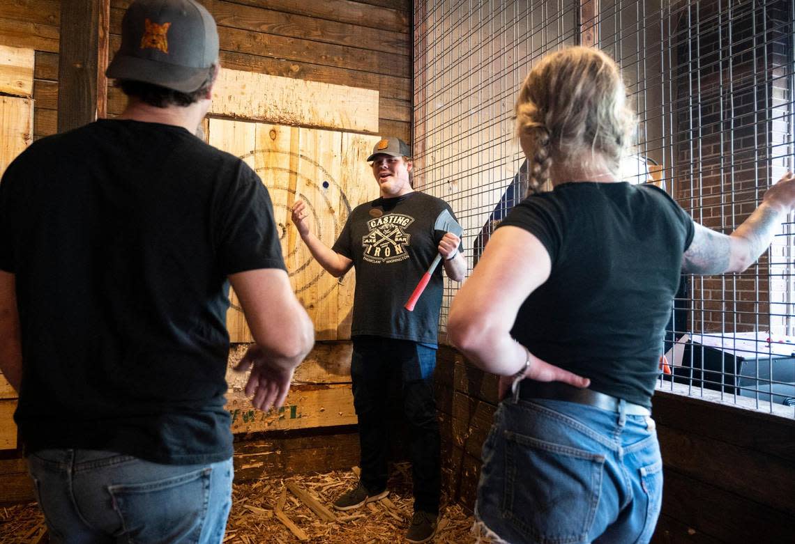 Casting Iron employee Duncan Ranft teaches customers how to throw axes safely before letting them begin their session at Casting Iron in Enumclaw, Wash. on Friday, July 8, 2022.