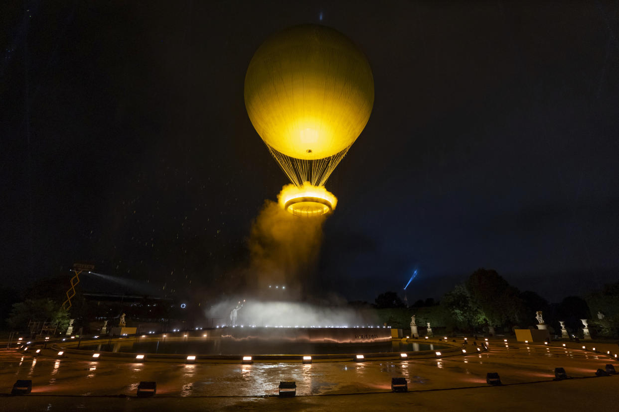 Teddy Riner and Marie-Jose Perec watch as the cauldron rises in a balloon in Paris, France, during the opening ceremony of the 2024 Summer Olympics, Friday, July 26, 2024. (AP Photo/David Goldman)