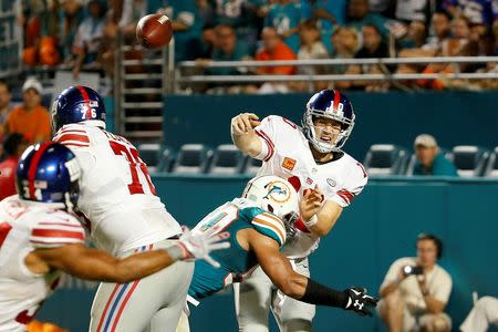 Dec 14, 2015; Miami Gardens, FL, USA; New York Giants quarterback Eli Manning (10) is tackled by Miami Dolphins defensive end Olivier Vernon (50) during the second half at Sun Life Stadium. Mandatory Credit: Steve Mitchell-USA TODAY Sports