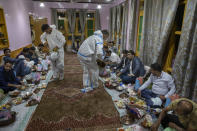 Kashmiri Wazas, or chefs, in personal protective equipment serve Wazwan during a wedding ceremony on outskirts of Srinagar, Indian controlled Kashmir, Tuesday, Sept. 15, 2020. The coronavirus pandemic has changed the way people celebrate weddings in Kashmir. The traditional week-long feasting , elaborate rituals and huge gatherings have given way to muted ceremonies with a limited number of close relatives attending. With restrictions in place and many weddings cancelled, the traditional wedding chefs have little or no work. The virus has drastically impacted the life and businesses in the region. (AP Photo/ Dar Yasin)