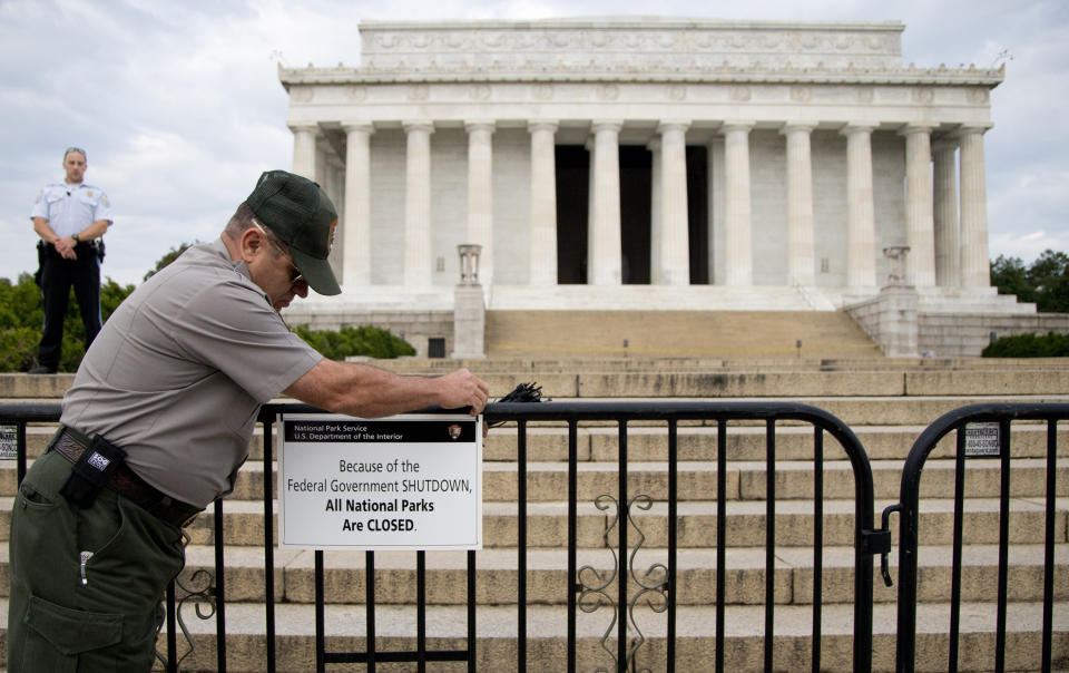 FILE - A US Park Police officer watches at left as a National Park Service employee posts a sign on a barricade closing access to the Lincoln Memorial in Washington, Tuesday, Oct. 1, 2013. (AP Photo/Carolyn Kaster)