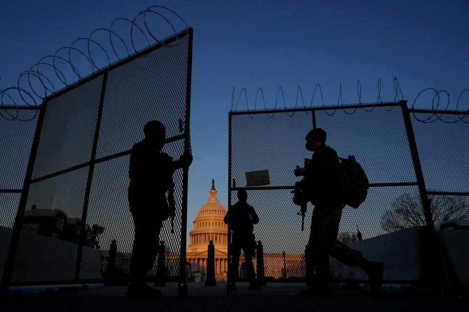Members of the National Guard open a gate in the razor wire-topped perimeter fence around the U.S. Capitol on Monday, allowing another member in at sunrise.