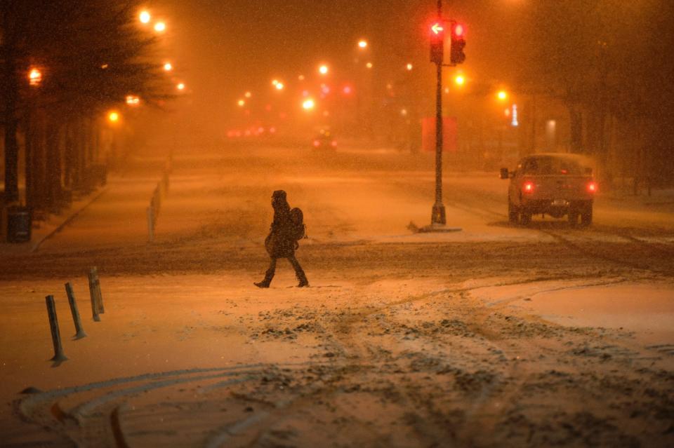 A woman crosses 15th Street during a snowstorm in Washington January 22, 2016. Thousands of flights were cancelled and supermarket shelves were left bare Friday as millions of Americans hunkered down for a winter storm expected to dump historic amounts of snow in the eastern United States.&nbsp;