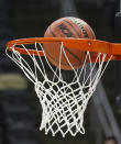 FILE - In this March 18, 2015, file photo, a basketball with the NCAA logo goes in on a shot by Northeastern during practice at the NCAA college basketball tournament in Pittsburgh. Coaches did the best they could to prepare for the big moment, yet still find themselves in a scramble once it actually happened. The NCAA announced last month that the season would begin on Nov. 25 and teams are still trying to fill all the holes in their schedules. (AP Photo/Keith Srakocic, File)