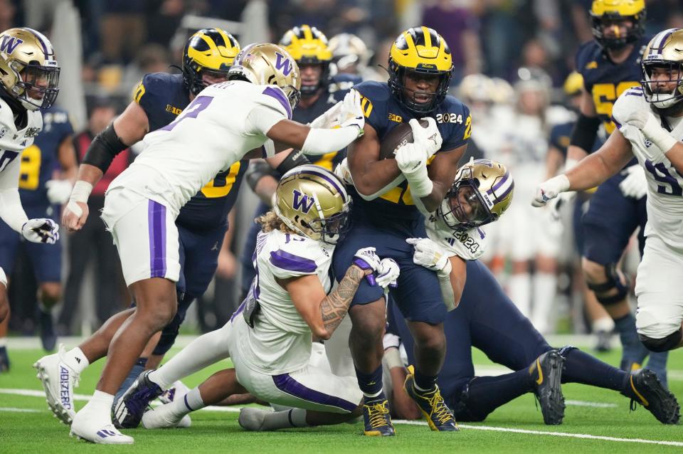 Michigan running back Kalel Mullings (20) is brought down by Washington defense in the second quarter during the College Football Playoff national championship game against Washington at NRG Stadium in Houston, Texas on Monday, January 8, 2024.