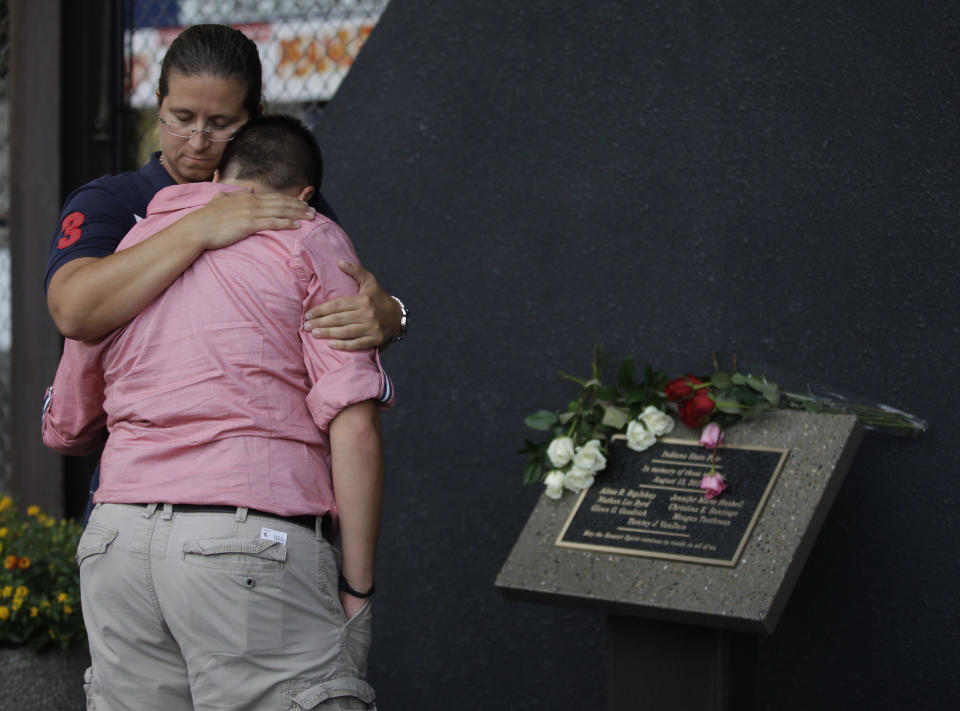 Two unidentified friends hug in front of a plaque honoring the six killed a year ago when stage rigging collapsed at the Indiana State Fair in Indianapolis, Monday, Aug. 13, 2012. A moment of silence for the victims and injured was observed at the fair at the time of the collapse. (AP Photo/Michael Conroy)